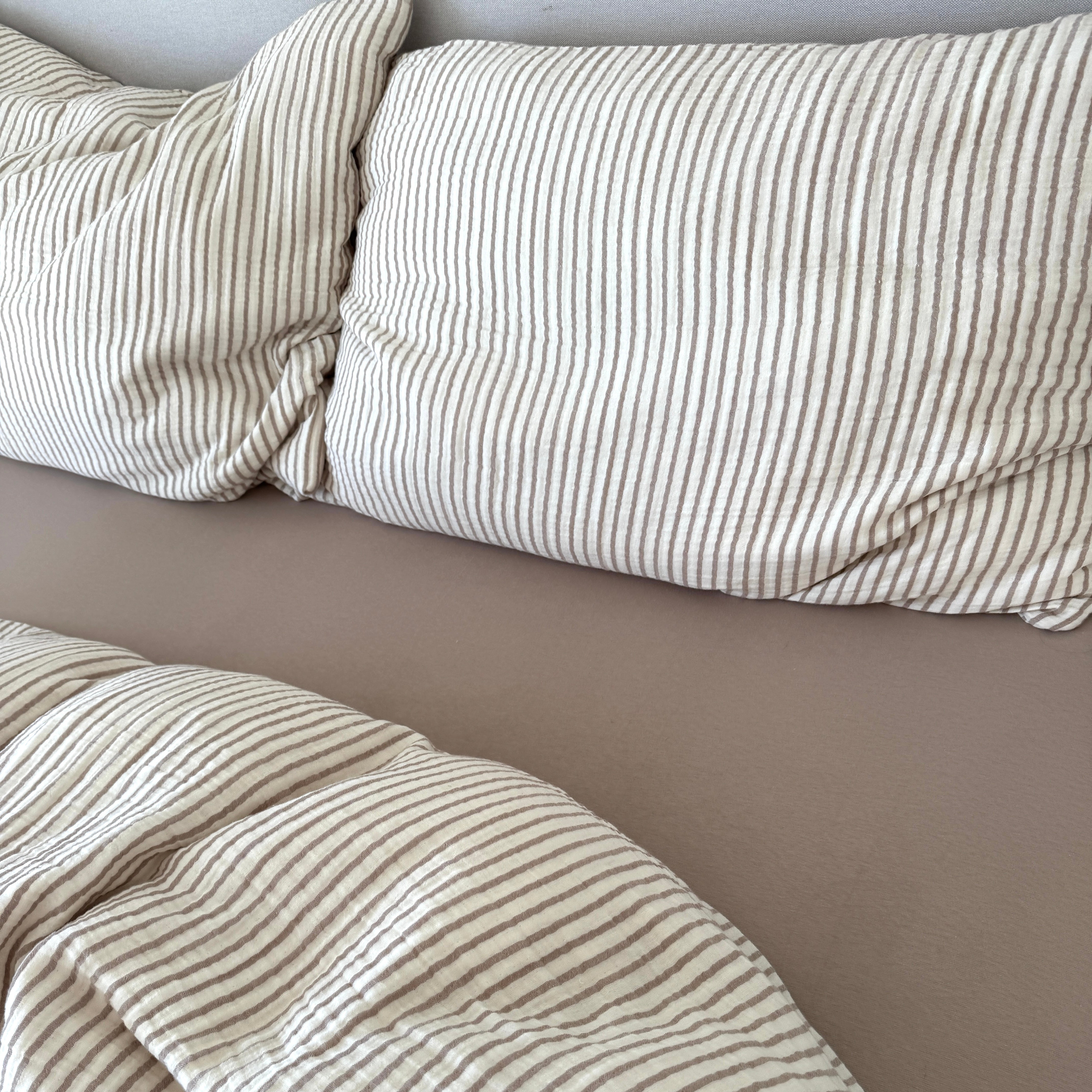 Gestreifte Bettwäsche mit taupefarbenem Fixleintuch und Kissen, dazu passender Duvetbezug in Taupe und Ecru