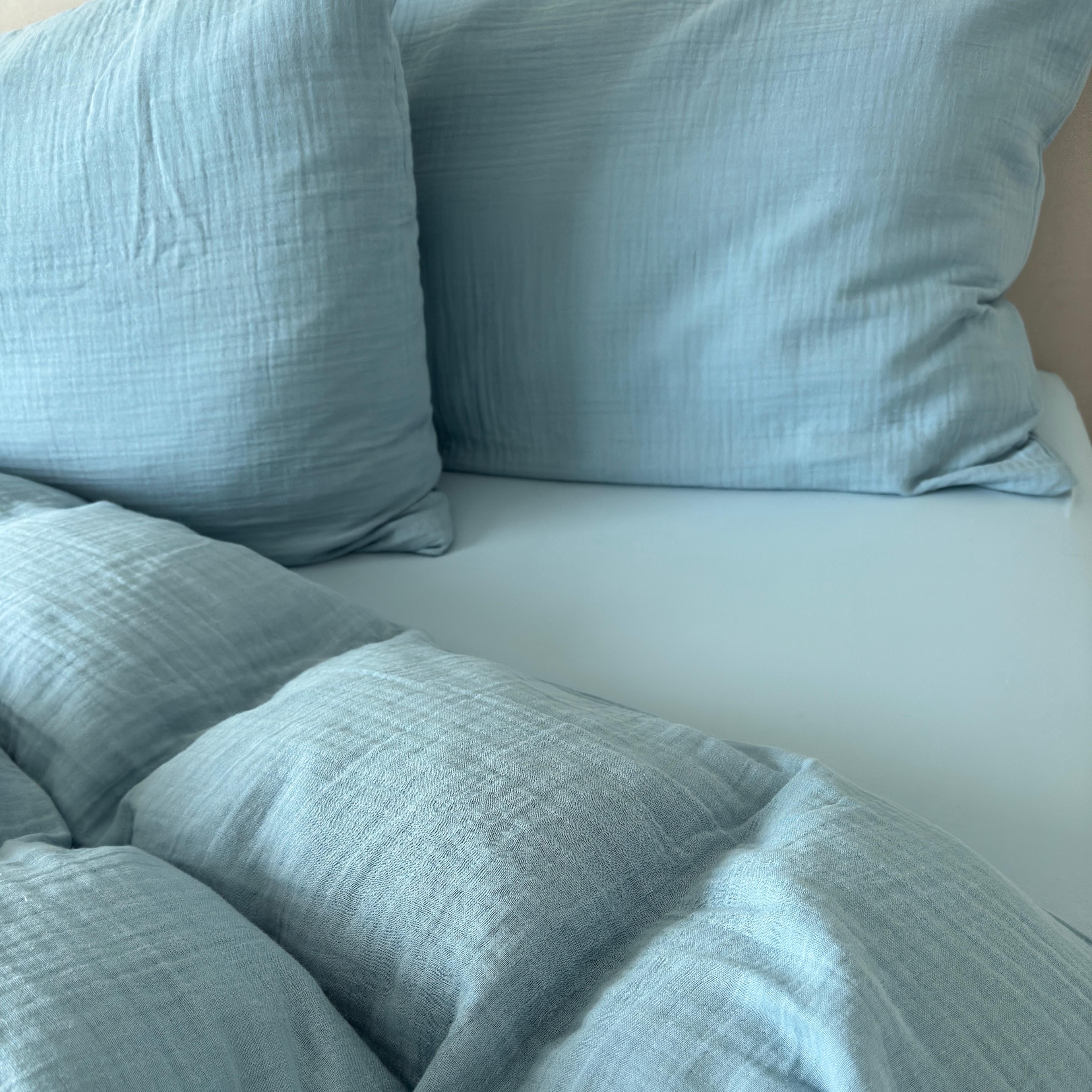 Himmelblaue Musselin Bettwäsche als Set mit Kissen und passendem Fixleintuch auf dem Bett