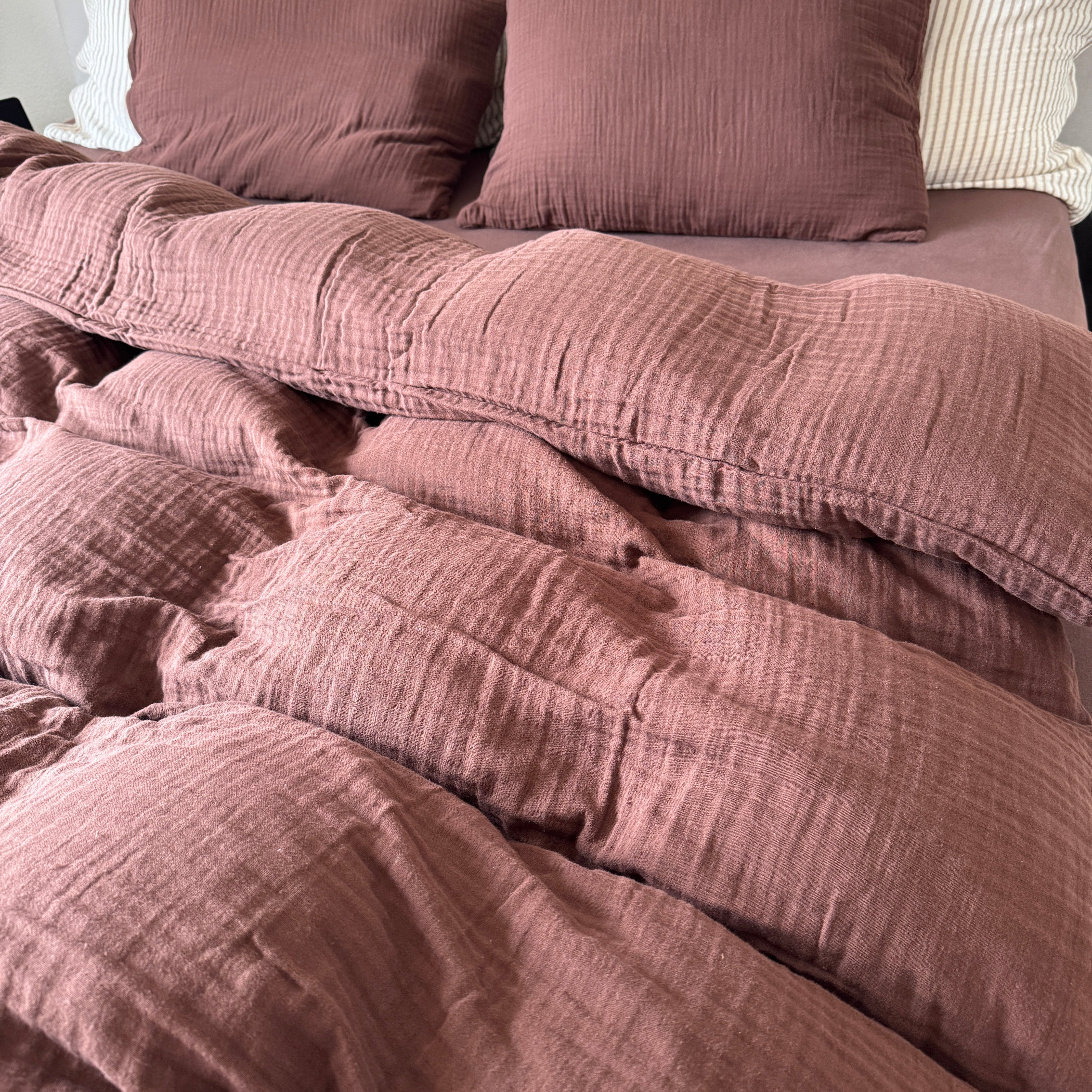 Mokka Musselin Bettwäsche mit passendem Kissen und Fixleintuch in einheitlicher Farbe auf dem Bett.
