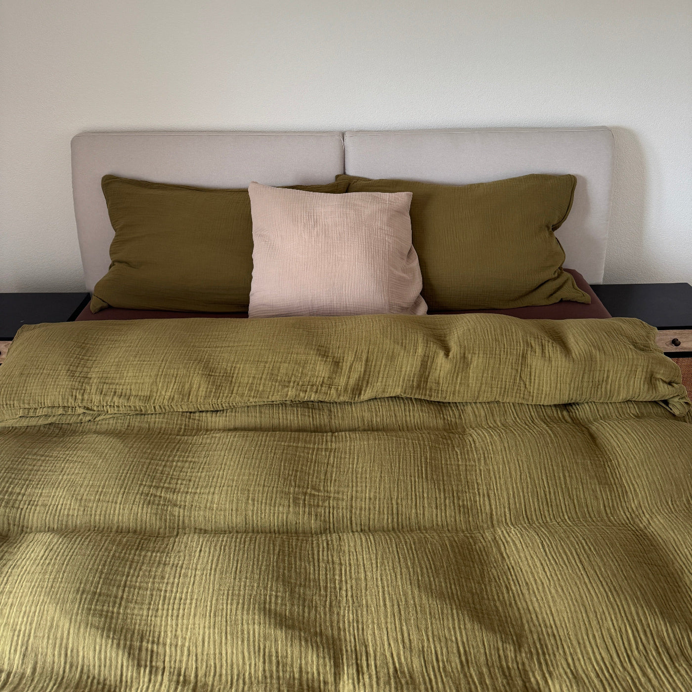 Olivgrüne Bettwäsche auf dem Bett verteilt mit sanfter Stoffstruktur