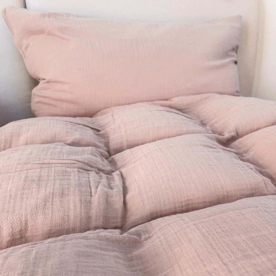 Puderrosa Musselin Duvetbezug und Kissenbezug auf dem Bett ausgelegt