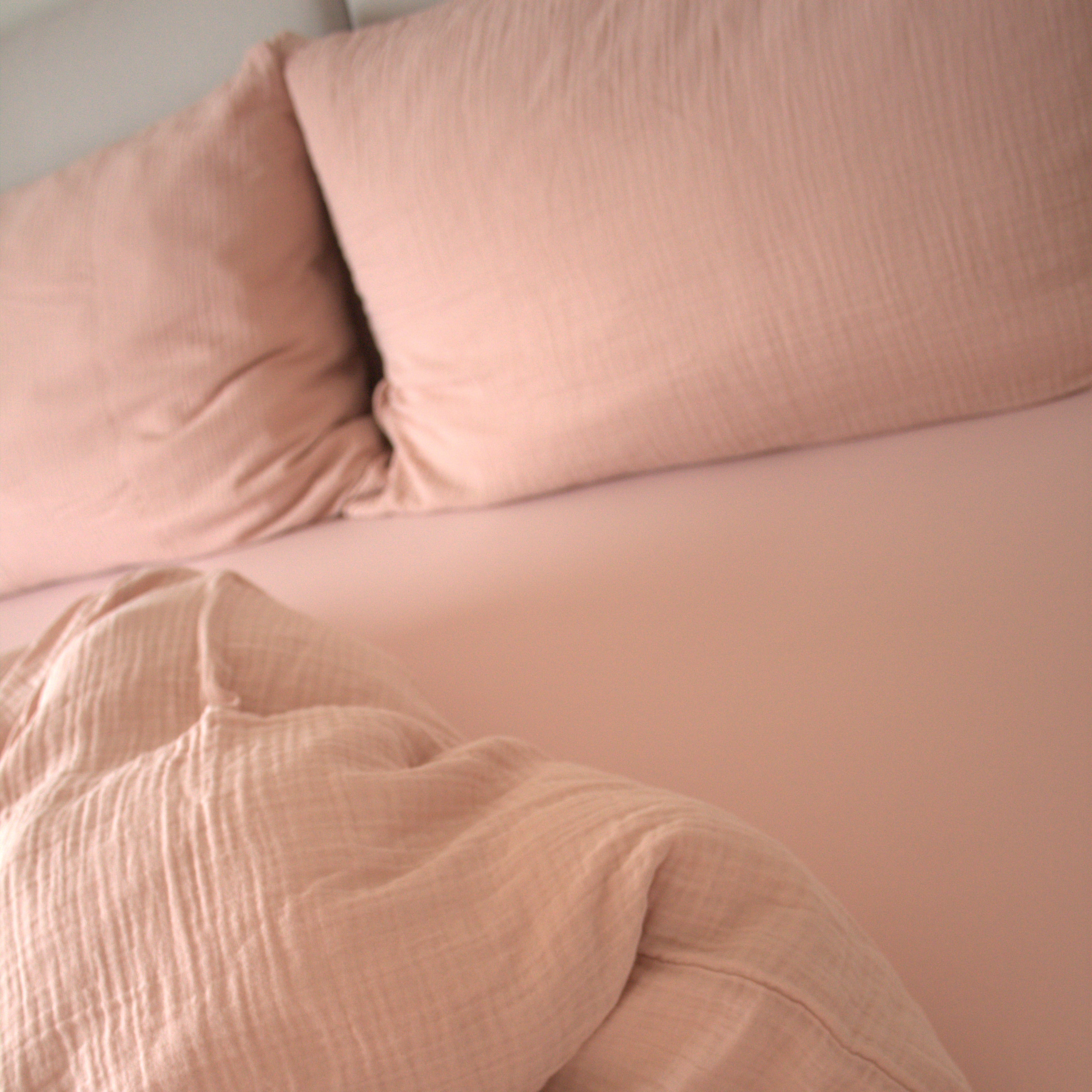Puderrosa Musselin Bettwäsche Set mit Kissen und Fixleintuch auf dem Bett präsentiert